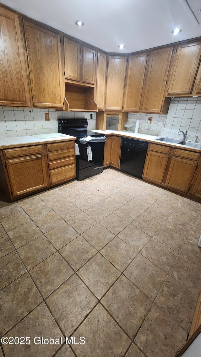 kitchen featuring backsplash, light tile patterned floors, black appliances, and sink