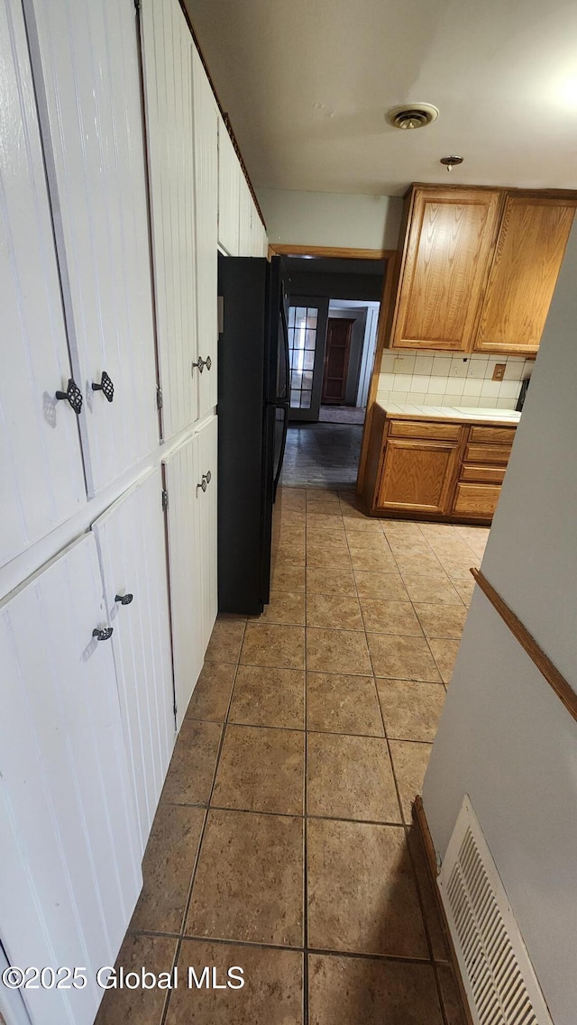 kitchen with light tile patterned floors, tile counters, and black refrigerator