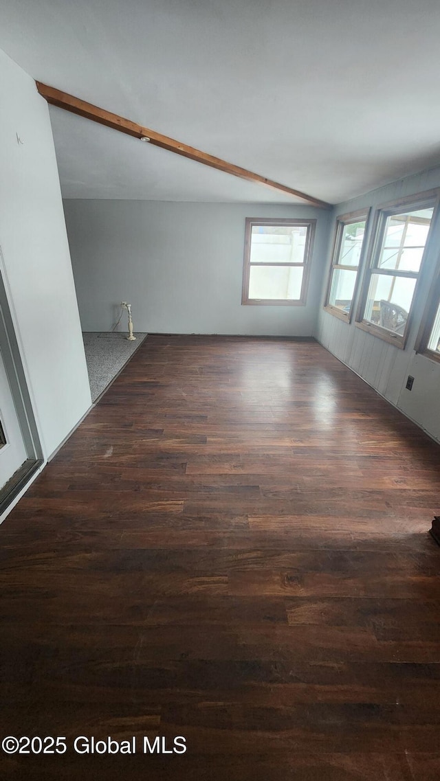 spare room with beam ceiling and dark wood-type flooring