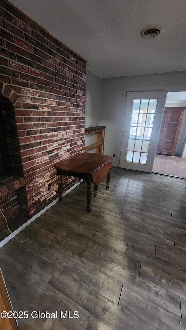 unfurnished dining area featuring dark wood-type flooring and brick wall