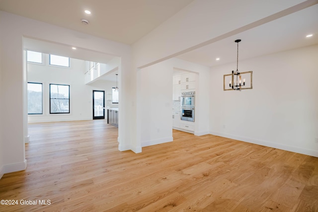 empty room with light wood-type flooring and an inviting chandelier