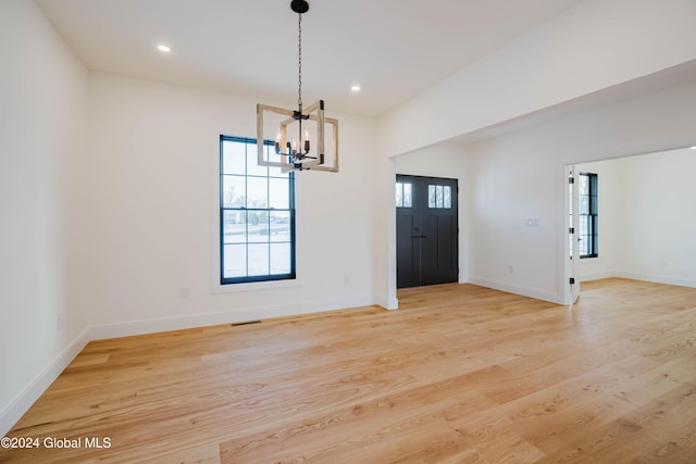 unfurnished dining area with a chandelier and light hardwood / wood-style flooring