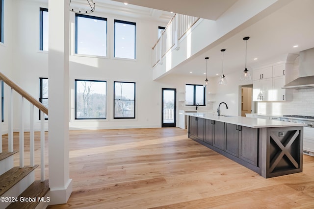 kitchen with white cabinetry, a spacious island, decorative light fixtures, decorative backsplash, and light wood-type flooring