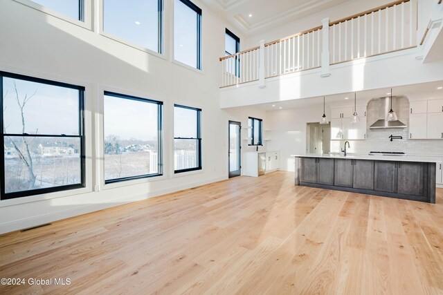 unfurnished living room with light hardwood / wood-style floors, a towering ceiling, and sink