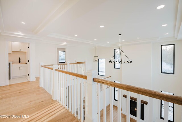 hallway featuring an inviting chandelier, crown molding, sink, and light hardwood / wood-style flooring