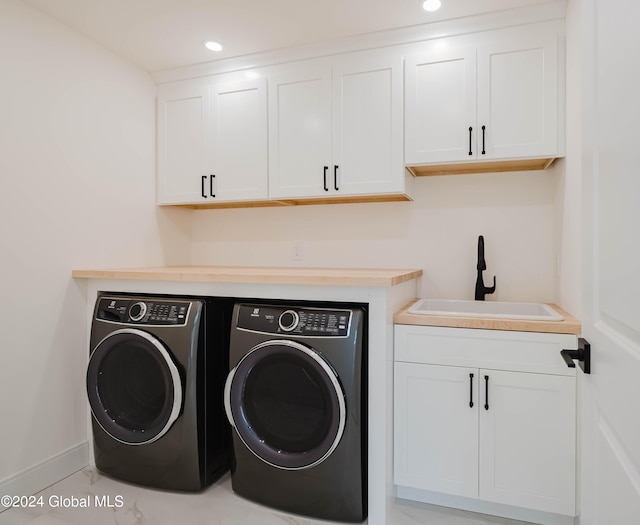 clothes washing area with washing machine and clothes dryer, sink, and cabinets