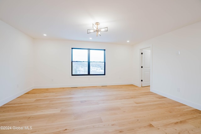 spare room featuring light hardwood / wood-style flooring and a notable chandelier