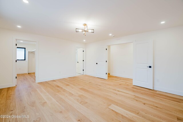 unfurnished room with a notable chandelier and light wood-type flooring