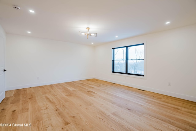 unfurnished room featuring light hardwood / wood-style floors and an inviting chandelier