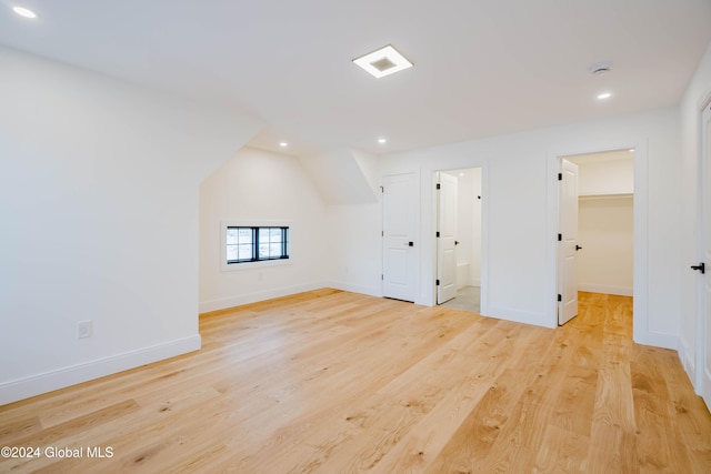 additional living space featuring light wood-type flooring and vaulted ceiling