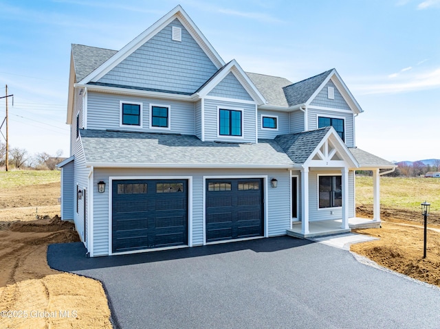 view of front of home featuring a shingled roof, an attached garage, a porch, and driveway