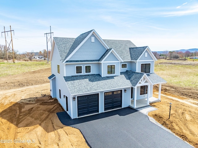 view of front of house featuring aphalt driveway, a porch, roof with shingles, and a garage