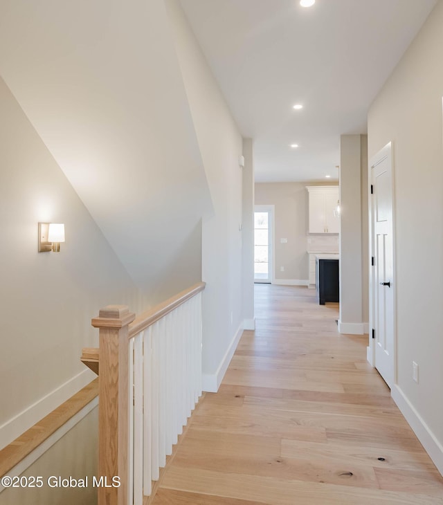 hallway with an upstairs landing, baseboards, light wood-style floors, and recessed lighting