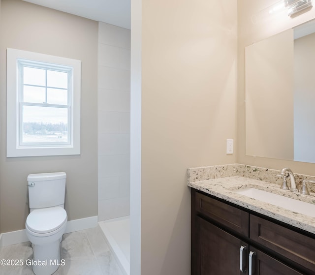 bathroom with baseboards, toilet, vanity, and a walk in shower