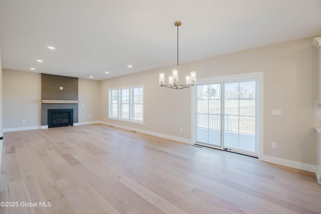 unfurnished living room featuring light wood finished floors, baseboards, recessed lighting, and a chandelier