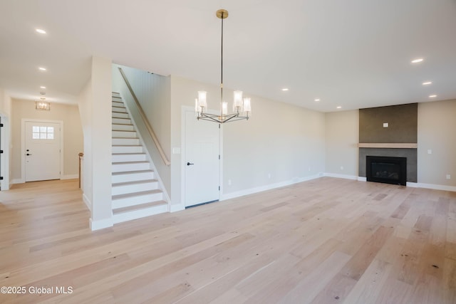 unfurnished living room featuring recessed lighting, light wood finished floors, and stairs