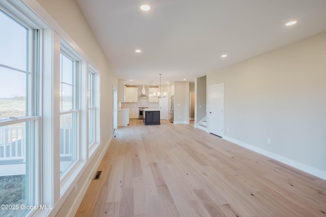 unfurnished living room with recessed lighting, stairway, visible vents, light wood-type flooring, and a chandelier
