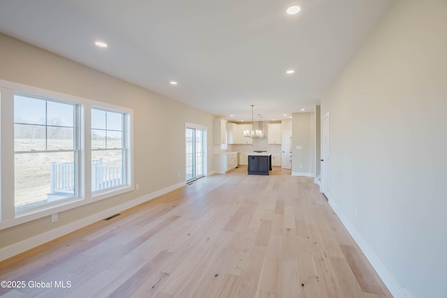 unfurnished living room featuring light wood finished floors, baseboards, visible vents, recessed lighting, and a notable chandelier