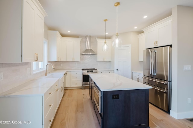 kitchen featuring wall chimney exhaust hood, light wood finished floors, stainless steel appliances, and a sink