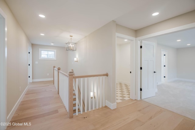 hallway featuring recessed lighting, light wood-style flooring, baseboards, and an upstairs landing