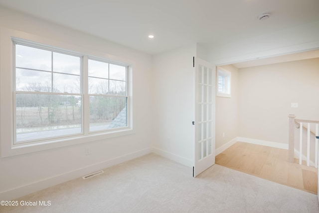 empty room with carpet floors, visible vents, and baseboards