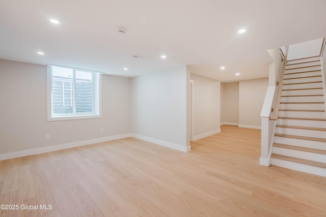 below grade area with recessed lighting, light wood-style flooring, baseboards, and stairs