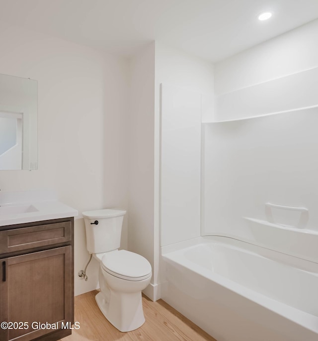 full bath with wood finished floors, toilet, vanity, and shower / washtub combination