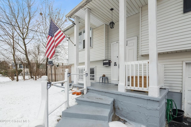 snow covered property entrance with covered porch