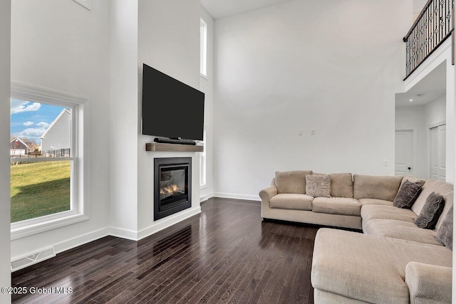 living room with dark hardwood / wood-style flooring and a towering ceiling