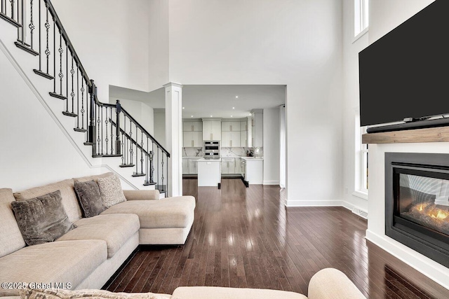 living room with ornate columns, a towering ceiling, and dark hardwood / wood-style floors