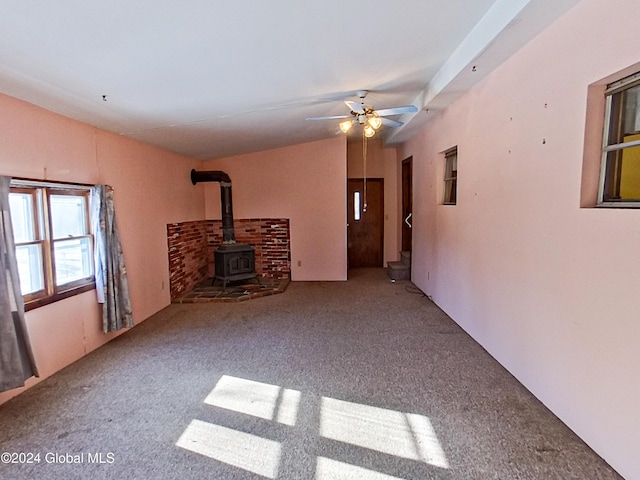 unfurnished living room featuring ceiling fan, a wood stove, and carpet floors