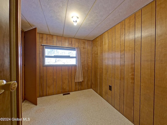 carpeted empty room with wood walls and a textured ceiling