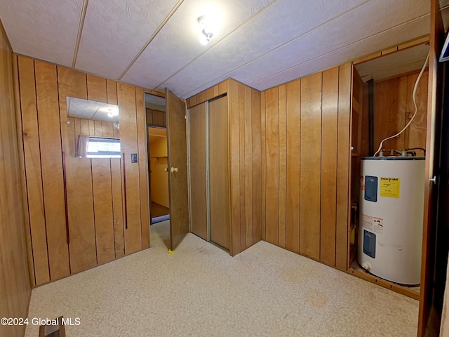 basement with carpet flooring, electric water heater, and wooden walls