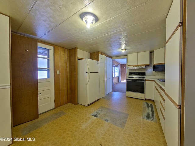 kitchen featuring white cabinets, white appliances, plenty of natural light, and wood walls