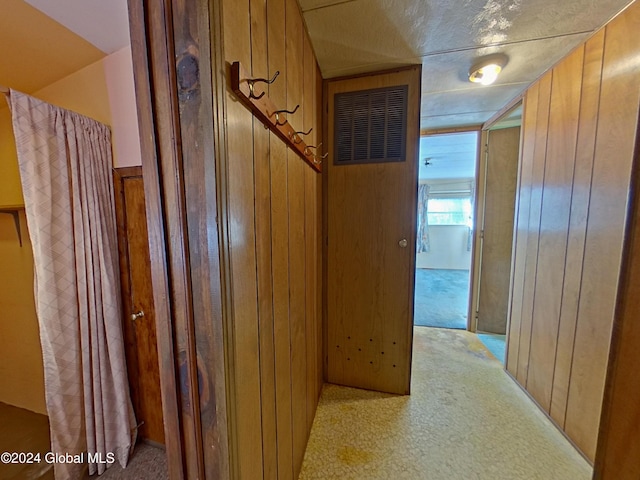 hallway featuring a textured ceiling and wooden walls