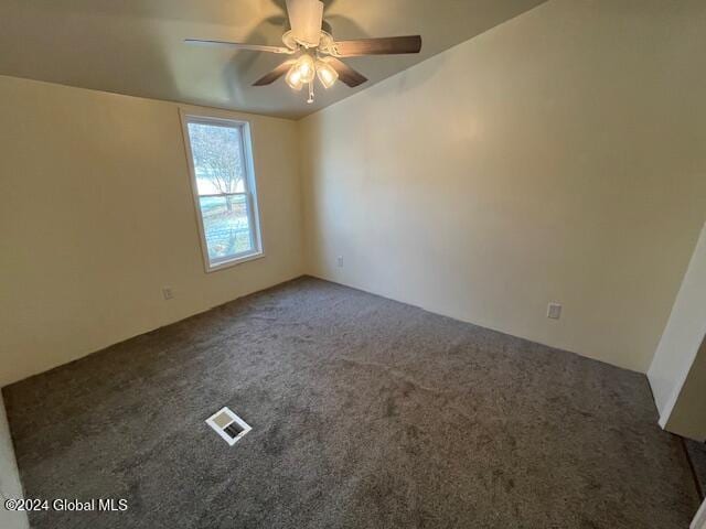 spare room featuring dark carpet and ceiling fan