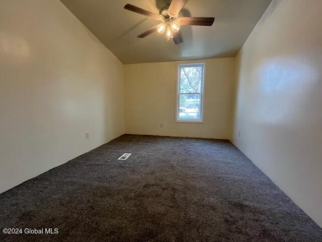 spare room with ceiling fan, lofted ceiling, and carpet floors