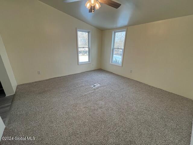 spare room with ceiling fan, lofted ceiling, and carpet floors