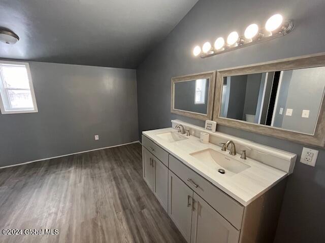 bathroom with hardwood / wood-style floors, vanity, and vaulted ceiling