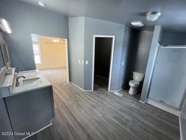 bathroom with hardwood / wood-style floors, vanity, toilet, and walk in shower