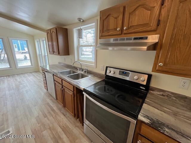 kitchen featuring sink, decorative light fixtures, vaulted ceiling, stainless steel range with electric cooktop, and light wood-type flooring