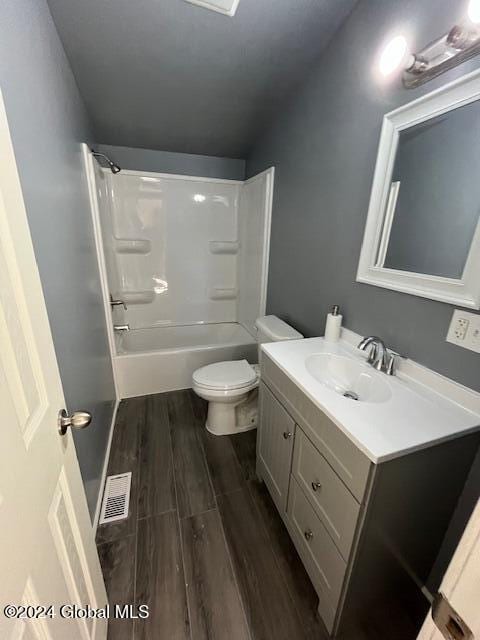 full bathroom with vanity,  shower combination, lofted ceiling, toilet, and wood-type flooring