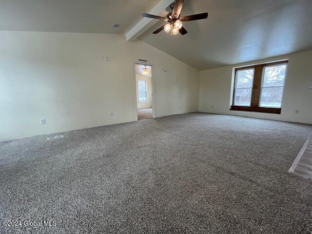 empty room featuring vaulted ceiling with beams, ceiling fan, and carpet floors