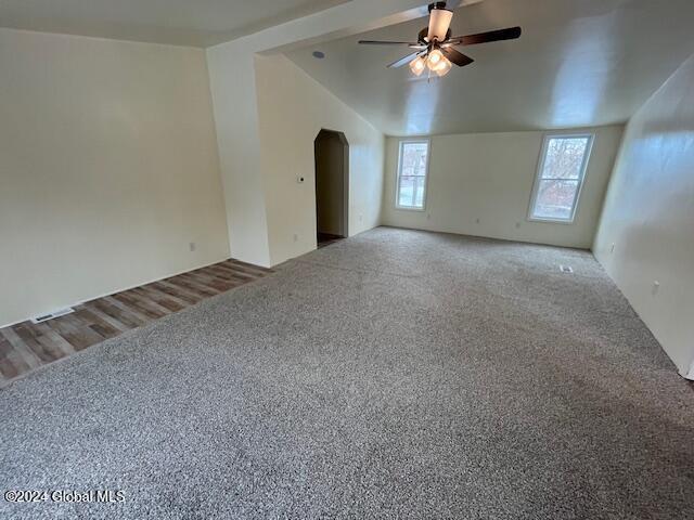 carpeted spare room featuring ceiling fan and vaulted ceiling