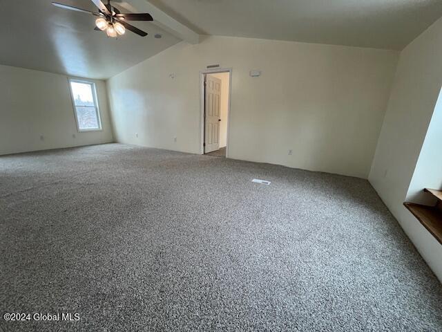 carpeted empty room featuring vaulted ceiling with beams and ceiling fan