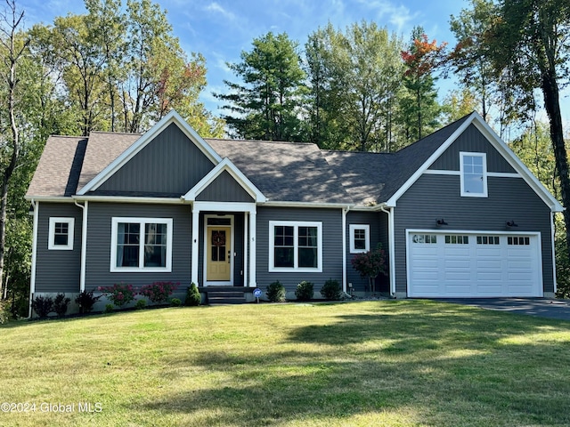 view of front of home featuring a garage, roof with shingles, aphalt driveway, and a front yard