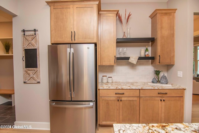 kitchen featuring light stone counters, freestanding refrigerator, backsplash, and open shelves