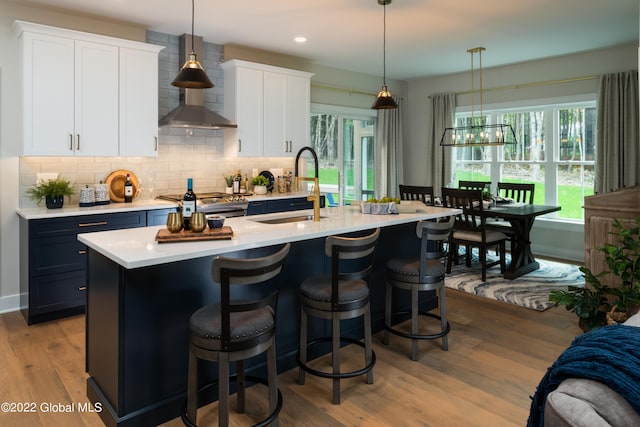 kitchen featuring light countertops, hanging light fixtures, a sink, and white cabinets