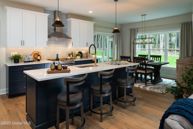 11 Huna Way Lot 16, Lake George, NY 12845 - kitchen featuring wall chimney exhaust hood, light countertops, decorative backsplash, wood finished floors, and a kitchen island with sink