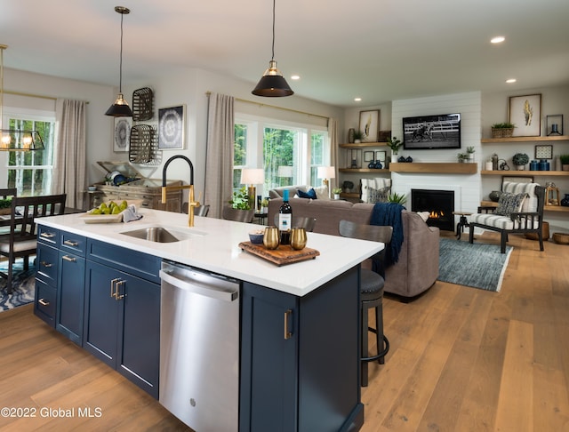 kitchen with dishwasher, an island with sink, blue cabinets, light countertops, and a sink